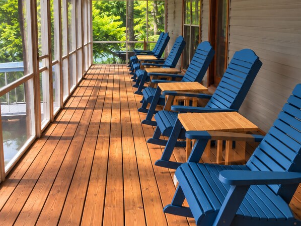 Un espace extérieur aménagé avec des sièges, protégé par un toit, doté d’un plancher en bois et de chaises bleues.