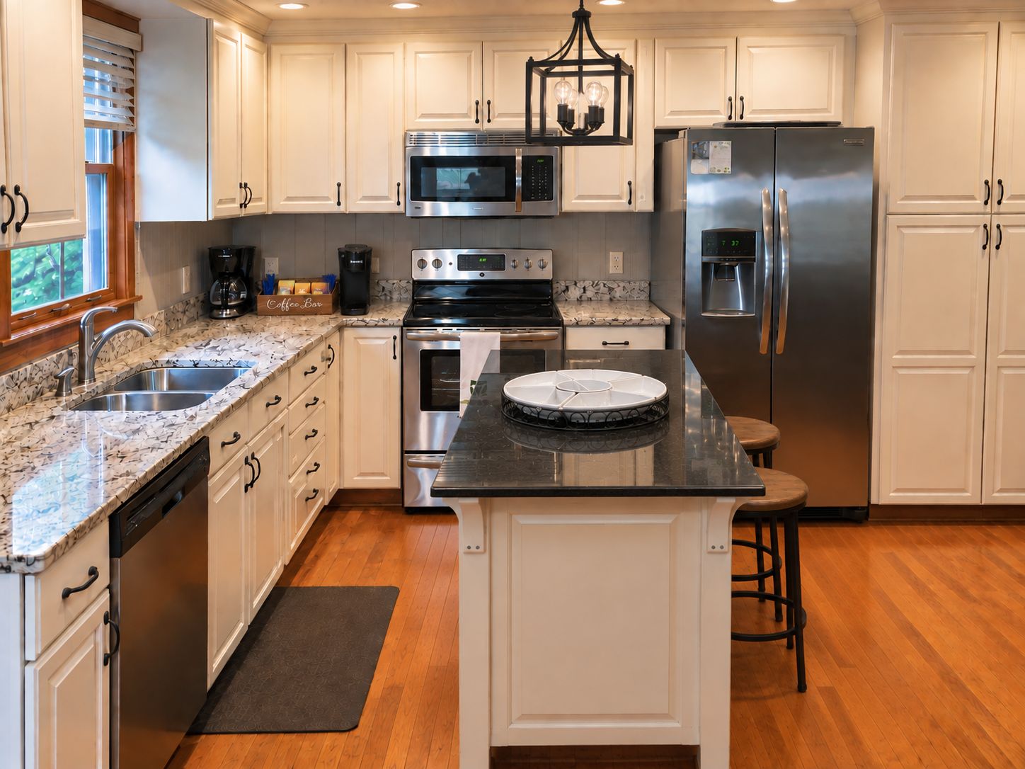 A modern kitchen with white cabinets, stainless steel appliances, a marble countertop, and a central island.
