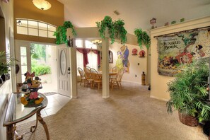 Cozy dining area with a table and chairs, featuring a large poster of 'The Jungle Book' and lush greenery.