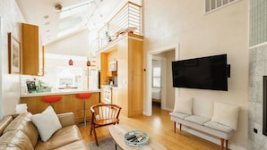 A spacious living area with a sofa, a coffee table, and a TV mounted on the wall.