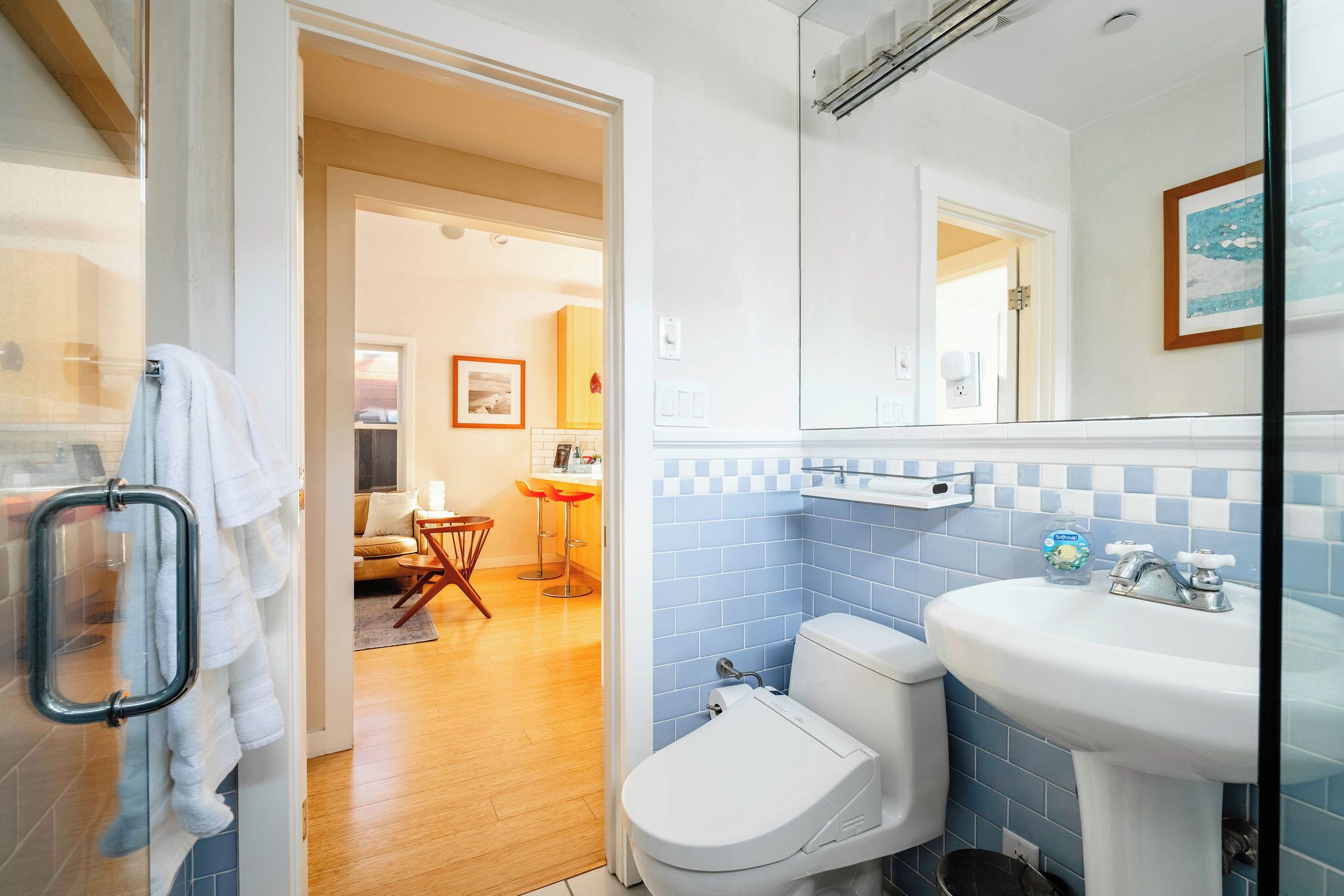 A bathroom with a white sink, blue-tiled walls, and a glass shower enclosure.
