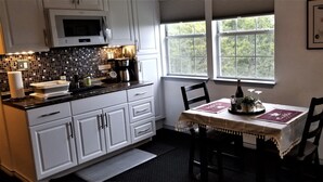 Cocina con armarios blancos, microondas y ventana con vistas a árboles.