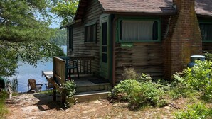 Eine rustikale Holzhütte mit Kamin und einer Veranda mit Sitzgelegenheiten.
