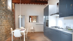 Una cocina moderna con armarios grises, una mesa de comedor blanca y una pared de piedra.