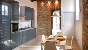 Una cocina moderna con armarios grises, horno empotrado y pared de piedra.