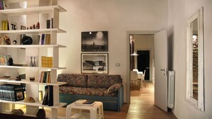 Una sala de estar con un sofá, estanterías y un cuadro en la pared.
