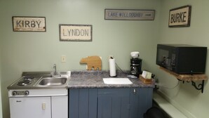 Une cuisine équipée d’une cuisinière, d’un évier et d’un four à micro-ondes. On peut voir des panneaux sur le mur indiquant les noms « Kirby », « Lyndon » et « Lake Willoughby ».