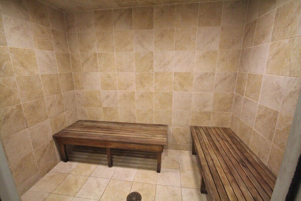 A small, tiled room with a bench and a wooden floor.