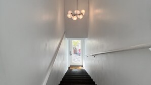 A staircase with a modern light fixture at the top, leading to a door with a doormat. - One Bedroom Apartment #3 in Historic Burns Square district, downtown Sarasota (Sarasota)