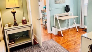 A room with a wooden floor, a white desk with a lamp, a painting on the wall, and a patterned rug. - One Bedroom Apartment #3 in Historic Burns Square district, downtown Sarasota (Sarasota)