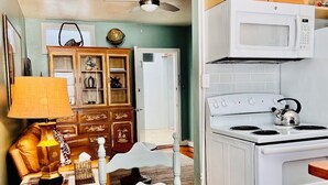 A kitchen with a white stove, a microwave, and a cabinet with decorative items. - One Bedroom Apartment #3 in Historic Burns Square district, downtown Sarasota (Sarasota)