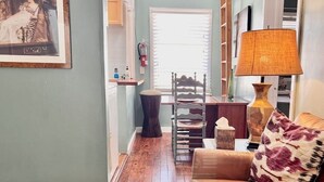 A living room with a leather sofa, a patterned throw pillow, a wooden chair, a lamp, and a framed picture on the wall. - One Bedroom Apartment #3 in Historic Burns Square district, downtown Sarasota (Sarasota)