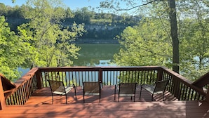 A wooden deck with chairs overlooking a lake, surrounded by trees. - Lakefront Cabin: Private Water Access, Boat Parking, Lake View & Wi-Fi (Burnside)