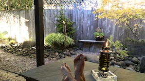 A patio with a table, a lantern, and a wooden fence in the background. - Gorgeous Pacific Northwest Private Lodge in Southeast Eugene (Eugene)