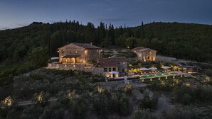 A large stone house with multiple rooms and a swimming pool, surrounded by forested hills. - ISOLA SERENA Newly Expanded Private Luxury Villa, Tuscany, Infinity Pool & Views (Castellina in Chianti)