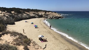 A beach with clear skies, rocky cliffs, and calm sea. - Breathtaking sunset, salt lake and Aegean sea view. 150m from magnificent beach. (NAXOS)