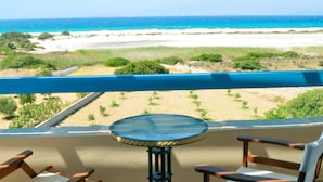 A balcony with a view of a beach, a round table, and two wooden chairs. - Breathtaking sunset, salt lake and Aegean sea view. 150m from magnificent beach. (NAXOS)