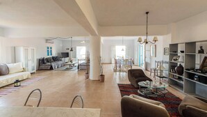A spacious living area with a sofa, chairs, a dining table, and a bookshelf. - Breathtaking sunset, salt lake and Aegean sea view. 150m from magnificent beach. (NAXOS)