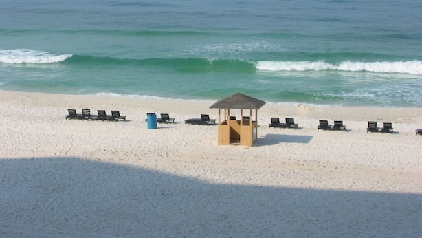 Ein Strand mit einer Holzhütte und mehreren Liegestühlen.