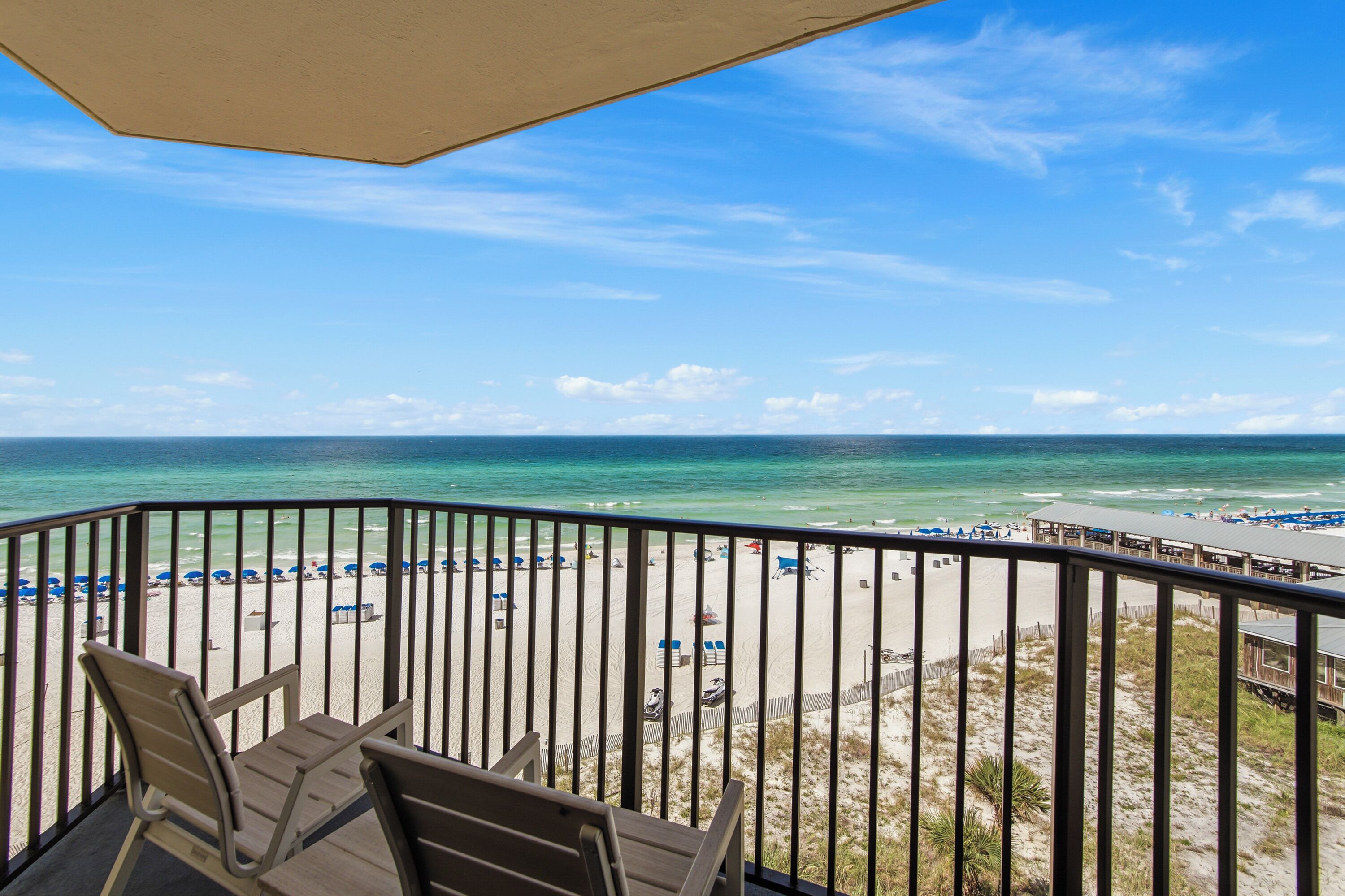 Een balkon met uitzicht op een strand, voorzien van stoelen en een tafel.