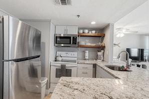 A modern kitchen with stainless steel appliances, a microwave, oven, and a coffee maker.