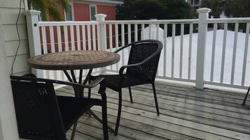 Relax in this charming outdoor space with a round table and two comfortable chairs, surrounded by a railing and wooden planks.