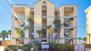 A multi-story hotel with balconies, palm trees, and a sign reading "Blue Dolphin."
