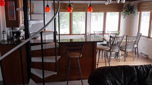 Una cocina moderna con una isla central, taburetes de madera y una escalera de caracol.