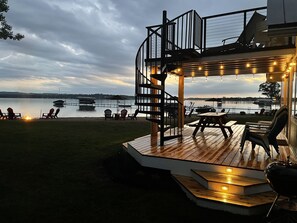 Una terraza con asientos al aire libre y vista al lago al anochecer.