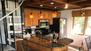 Una cocina moderna con una isla central, armarios de madera, electrodomésticos de acero inoxidable e iluminación colgante.