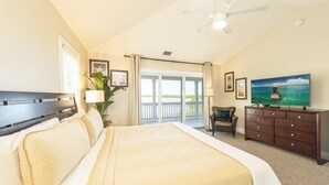 Ett hotellrum med en stor säng, en tv, ett skrivbord och utsikt över vattnet.