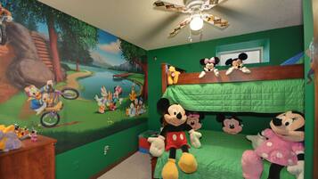 Cozy children's retreat with a Disney-themed mural, bunk bed, and desk for kids to play and learn.