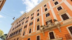 A multi-story building with a classic architectural style, featuring balconies with wrought iron railings and decorative moldings. - Modern Comfort, Poetic Charm (Roma)