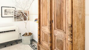 A wooden wardrobe with intricate carvings, a white radiator, and a potted tree in a corner. - Modern Comfort, Poetic Charm (Roma)
