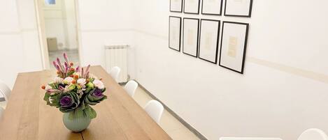 Een vergaderruimte met een houten tafel, witte stoelen, een whiteboard en ingelijste diploma’s aan de muur.