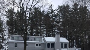 Una casa de dos pisos con un amplio jardín delantero cubierto de nieve.