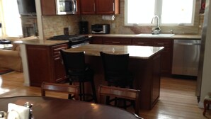 Una cocina moderna con armarios de madera, electrodomésticos de acero inoxidable y una isla central con asientos.
