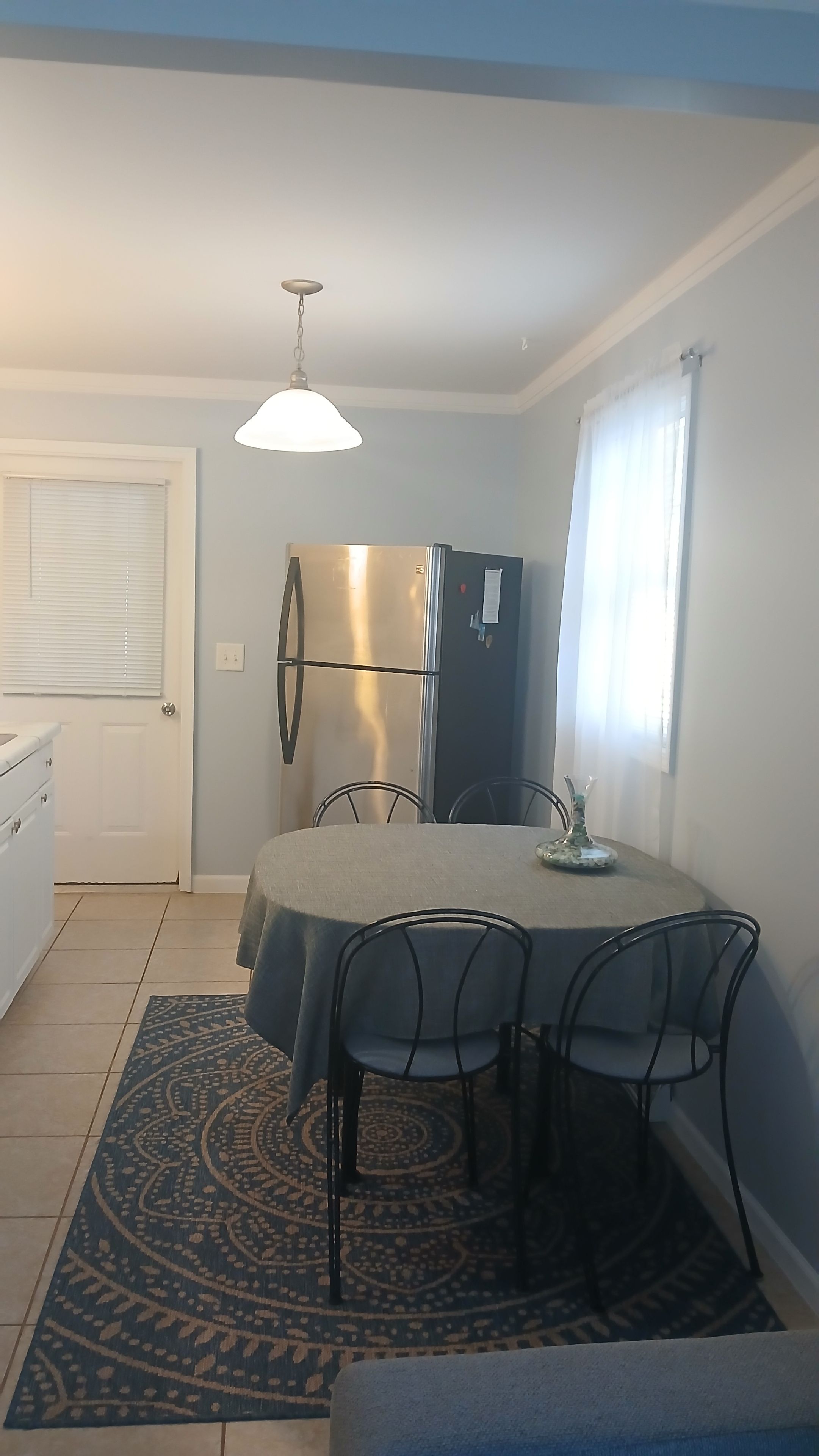 Un'area pranzo compatta con tavolo e sedie, un frigorifero e un tappeto decorato.