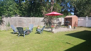 A backyard with a patio area, outdoor furniture, a barbecue grill, and a shed.
