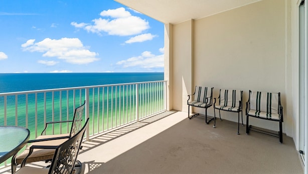 A balcony with a view of the ocean, a table, and three chairs. - 4th Newest Beachfront Condo! 100% No Smoking (Panama City Beach)