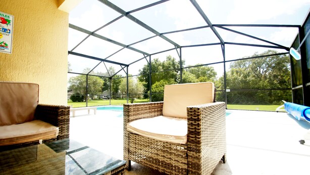 A covered outdoor seating area with wicker furniture and a view of a backyard. - Amazing villa - Close to Disneyworld (Clermont)