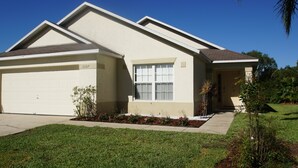 A single-story house with a garage, a front yard with a flower bed, and a small tree. - Amazing villa - Close to Disneyworld (Clermont)