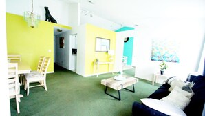 A living room with a sofa, chairs, a coffee table, and a dining area with a table and chairs. There is a hallway leading to a kitchen. - Amazing villa - Close to Disneyworld (Clermont)