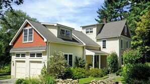 Une maison à deux étages avec un garage, une véranda et un jardin aménagé à l’avant, agrémenté d’un chemin en pierre.