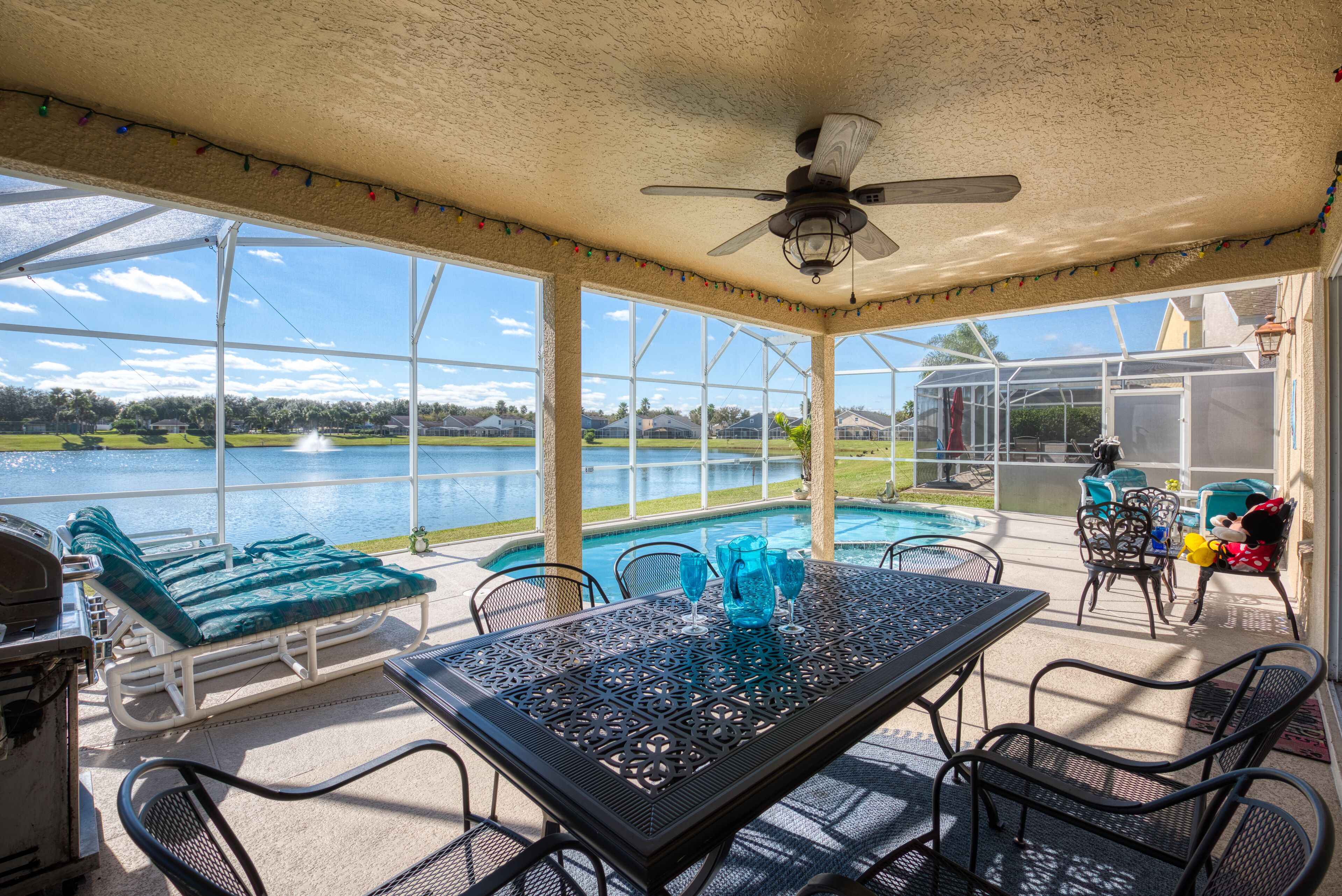Une terrasse couverte avec une piscine, des sièges d’extérieur et une vue sur le lac.