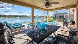 A covered patio with a pool, outdoor seating, and a view of the lake.
