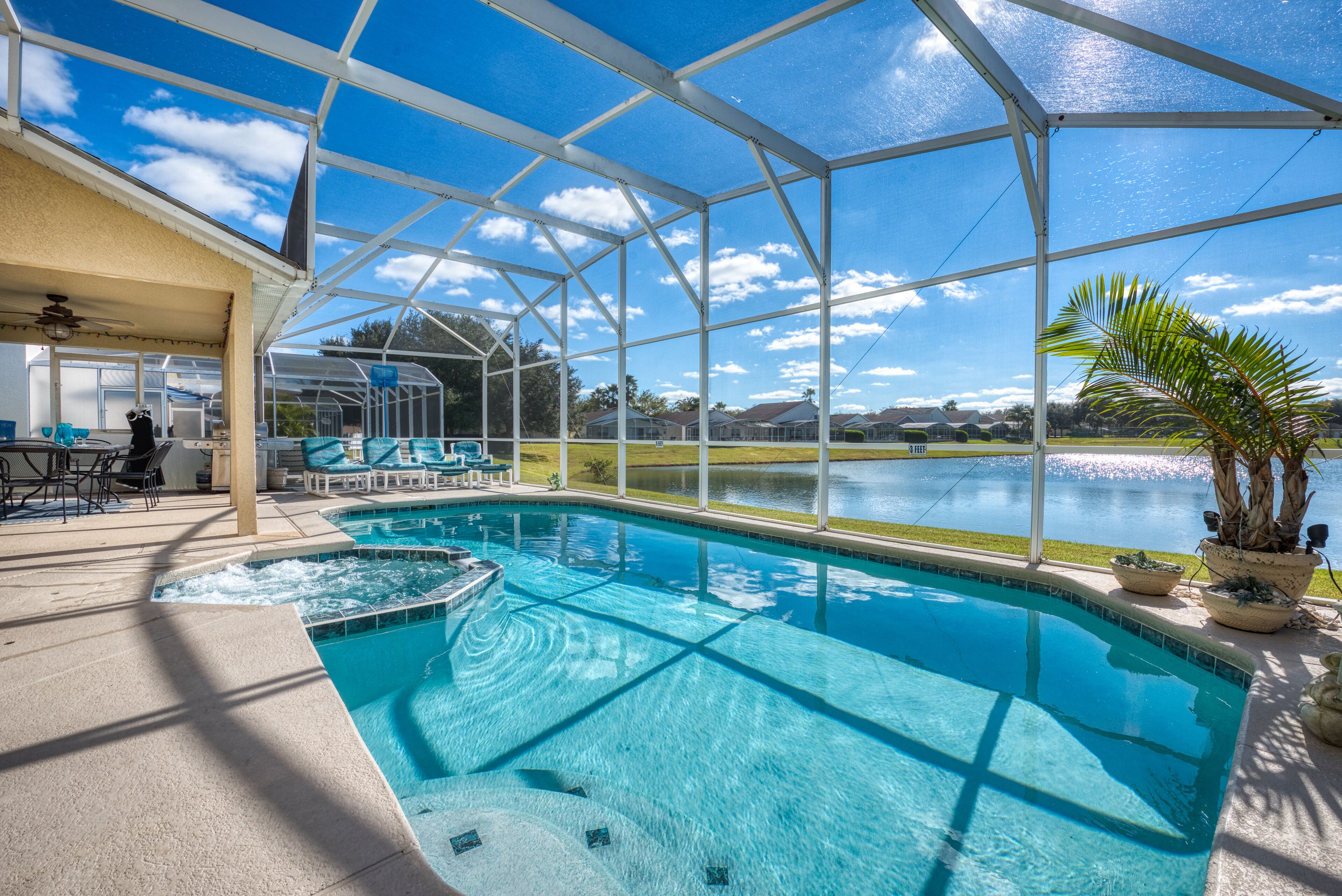 Un espace piscine offrant une vue dégagée sur un lac, un coin salon abrité et une piscine avec un jacuzzi.