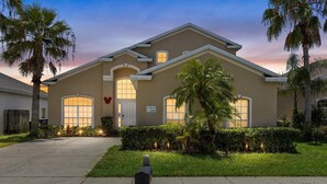 A two-story house with a beige exterior, large windows, and a well-maintained lawn.