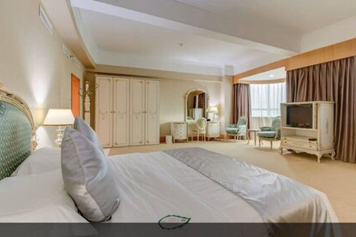 A hotel room with a large bed, a TV, a desk, and a wardrobe.