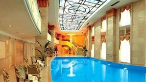 Een luxe binnenzwembad met glazen dak, versierde zuilen en klassieke architectuur.